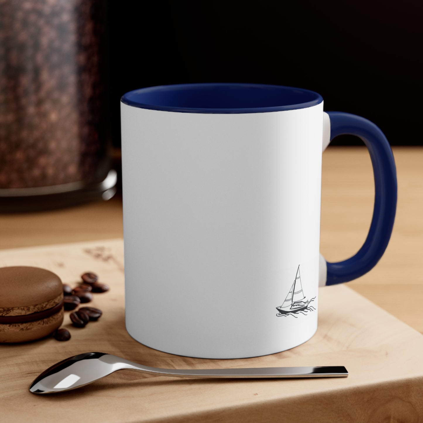 White Coffee Mug with Blue Handle and sailboat on front sitting on table