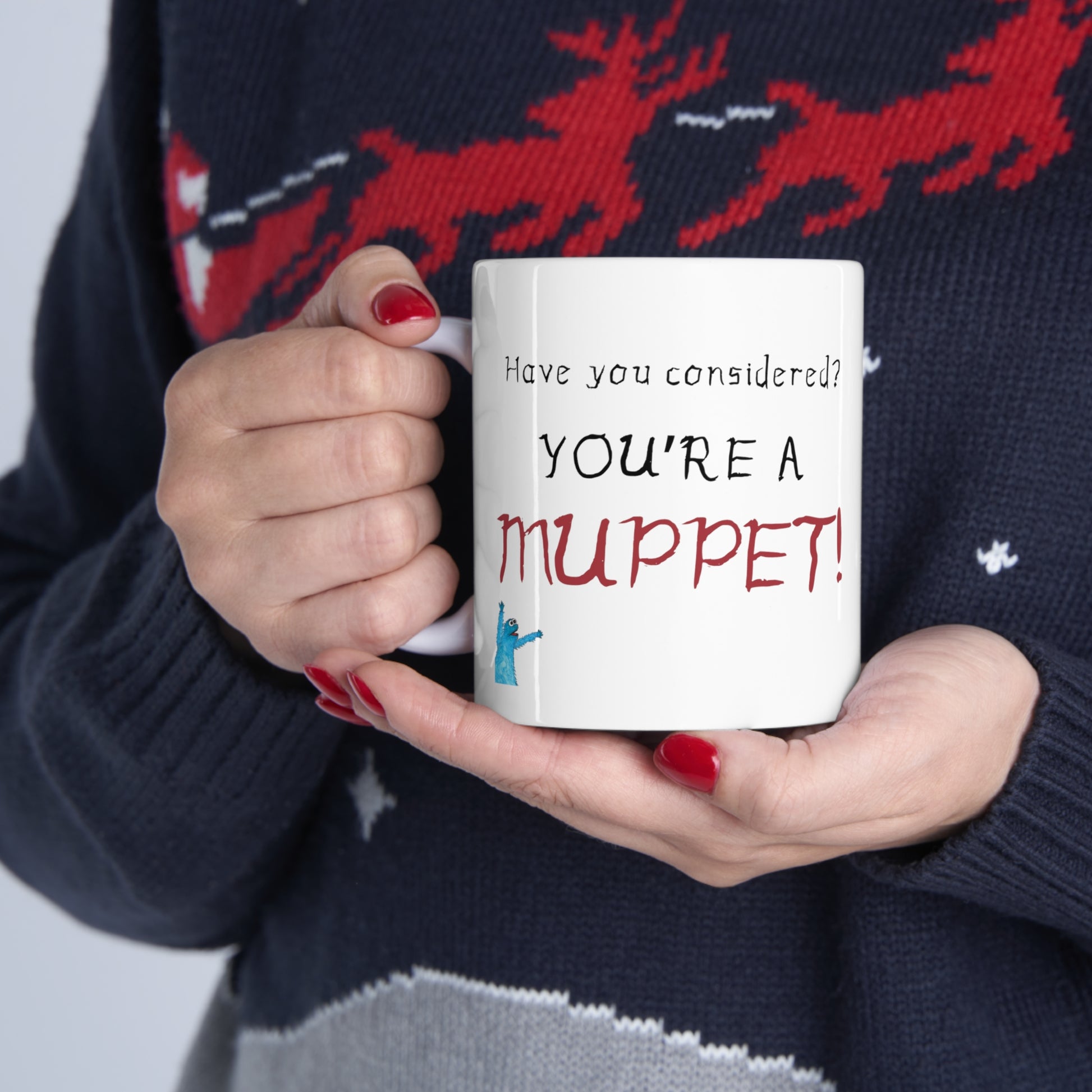 Woman in sweater holding a white Coffee Mug with "Have you considered? You're a Muppet!" text with a muppet 