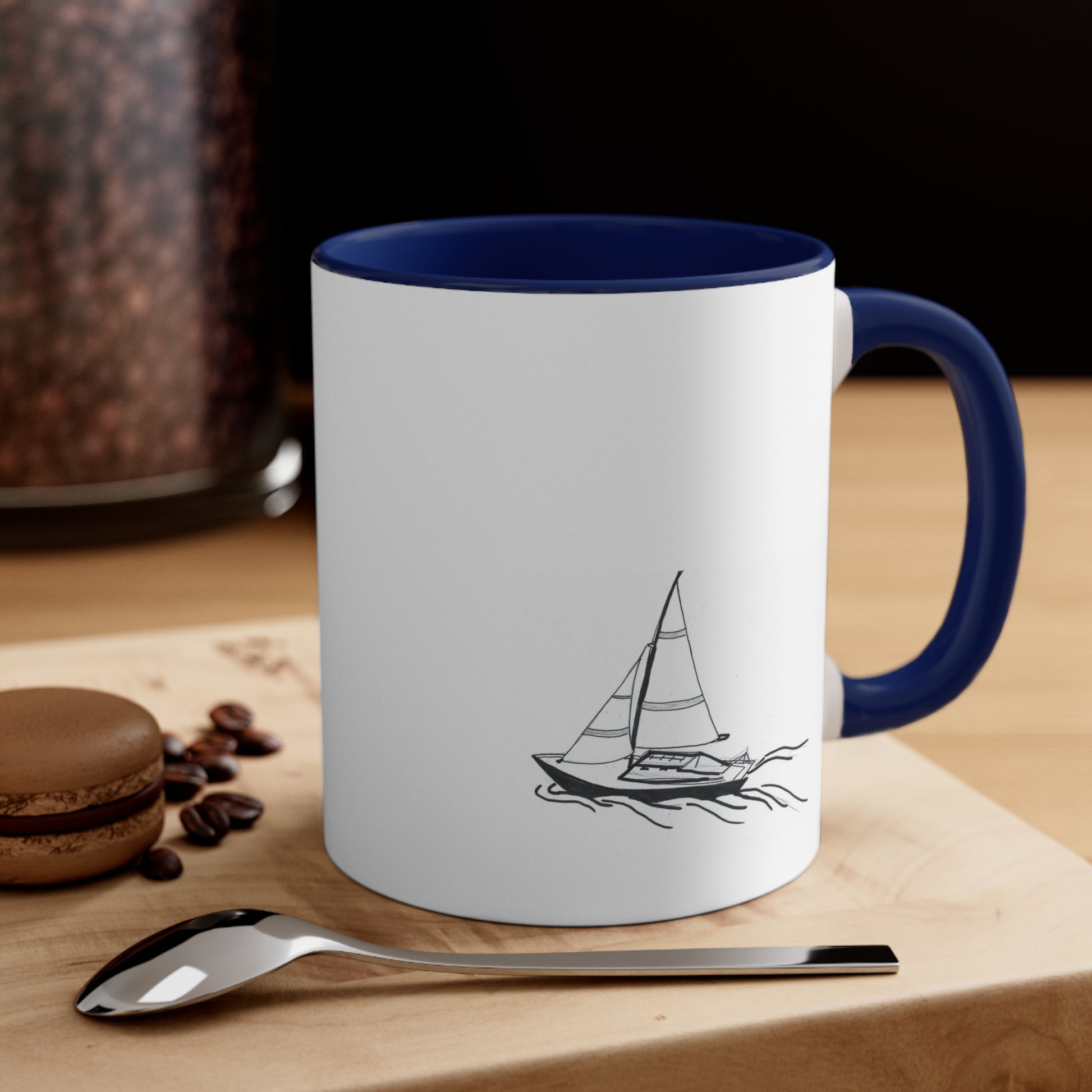 White and Blue Coffee Mug with Sailboat sitting on a table