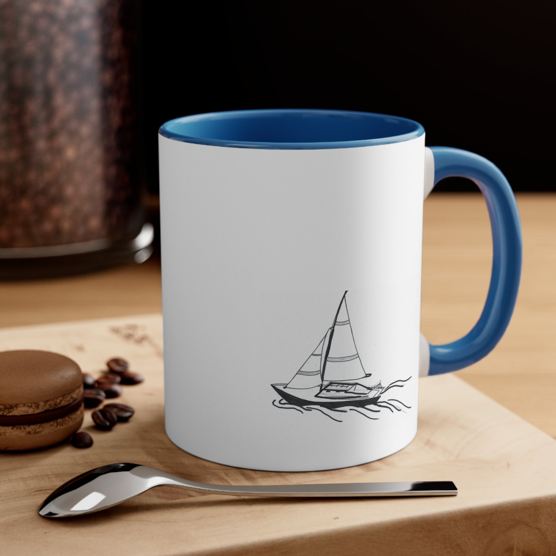 White and Light Blue coffee mug with sailboat on back sitting on a table